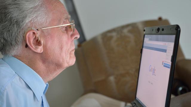 Älterer Herr arbeitet an einem Laptop.