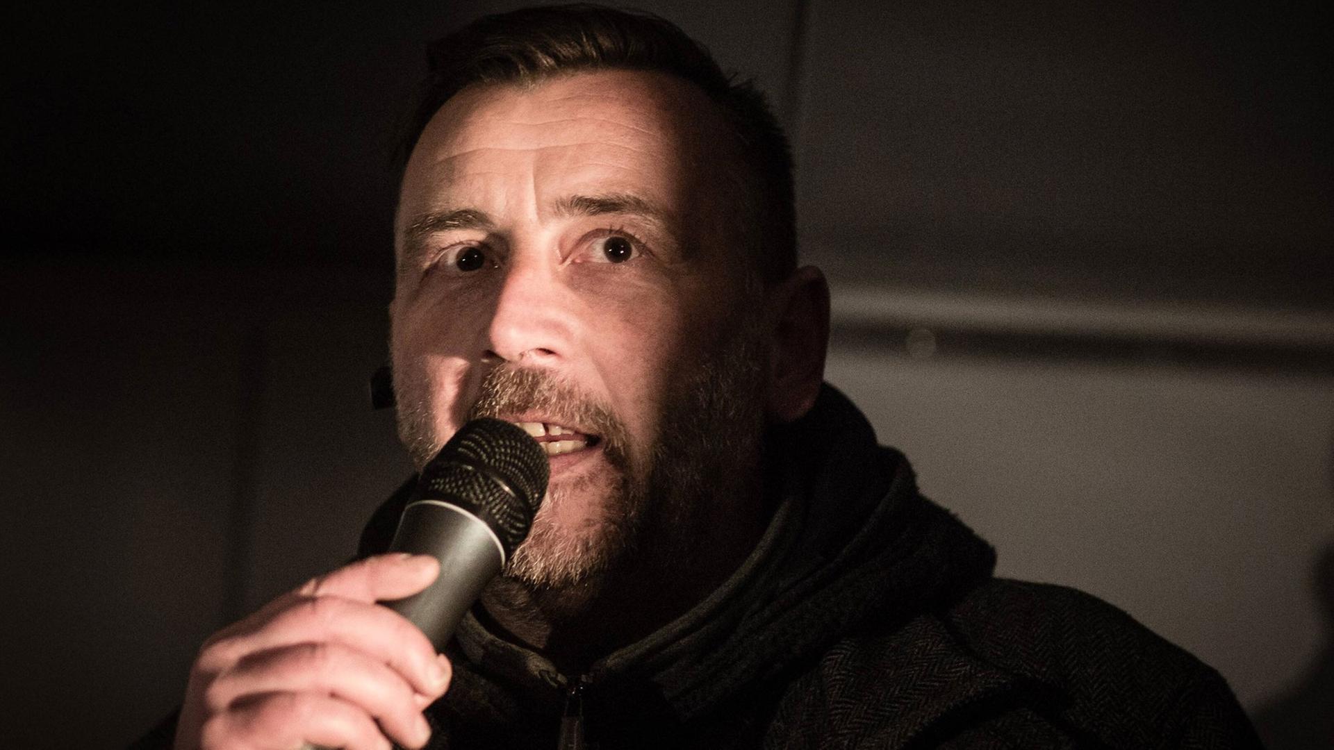 Pegida-Mitbegründer Lutz Bachmann in spärlichem Licht mit Mikrofon in der Hand. Pegida-Mitbegründer Lutz Bachmann in spärlichem Licht mit Mikrofon in der Hand.