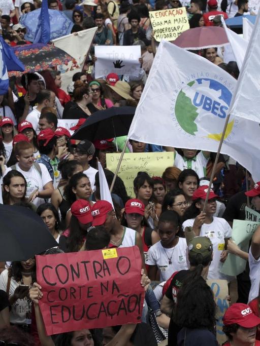 Demonstranten nehmen an einem landesweiten Bildungsstreik in Brasilia teil. Blick von oben auf eine Masse von Demonstranten. Sie schwenken Fahnen und halten Transparente hoch.