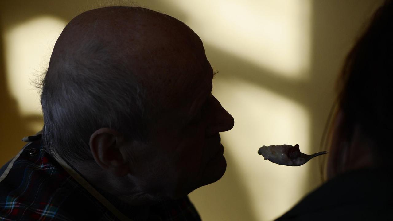 Ein Mann wird in Berlin im Seniorenpflegeheim pro vita Haus Rheingold von einem Pfleger gefüttert.