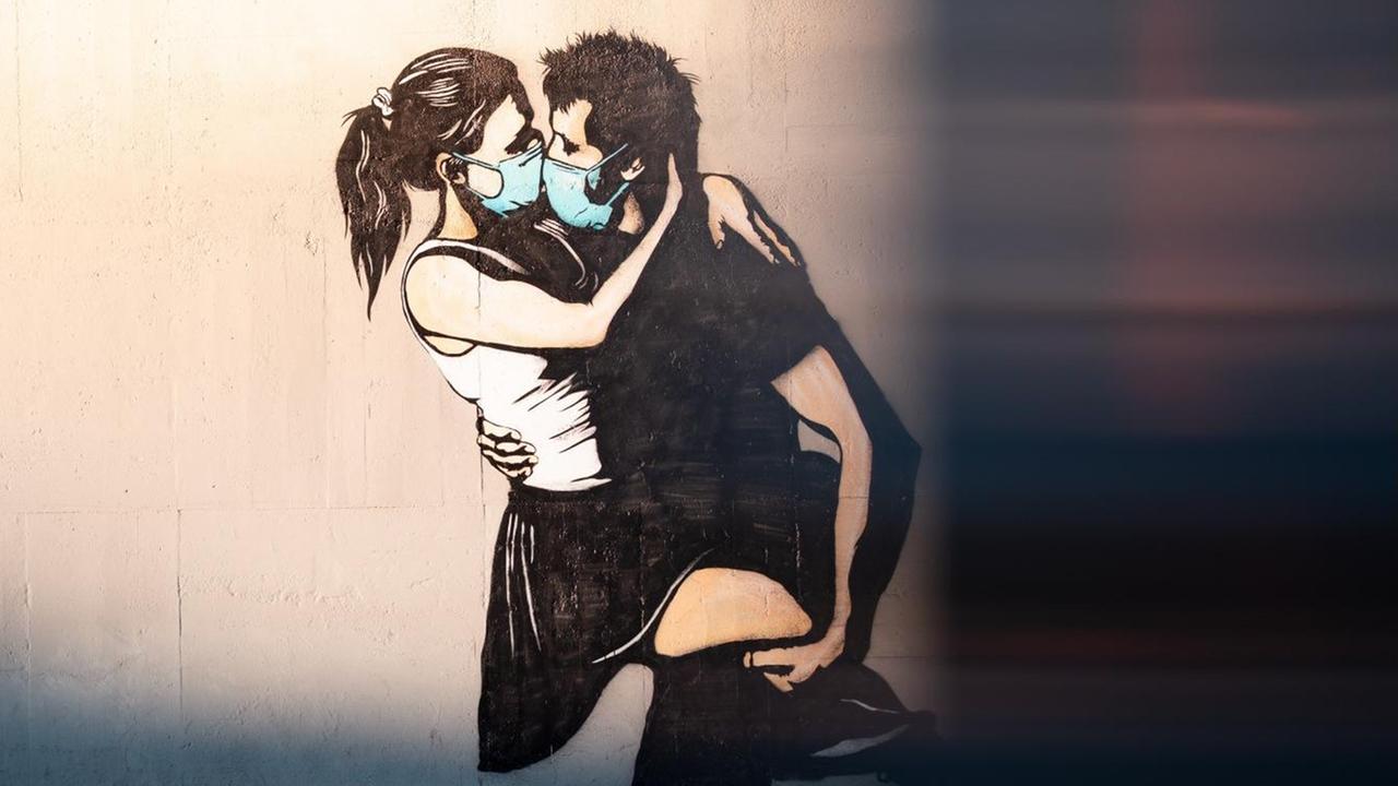 Street Art in Bryne, Norwegen. Auf einer Wand sieht man die Darstellung eines Pärchens, beide tragen medizinische Masken und sind im Begriff, sich zu küssen. Street Art in Bryne, Norwegen. Auf einer Wand sieht man die Darstellung eines Pärchens, beide tragen medizinische Masken und sind im Begriff, sich zu küssen.
