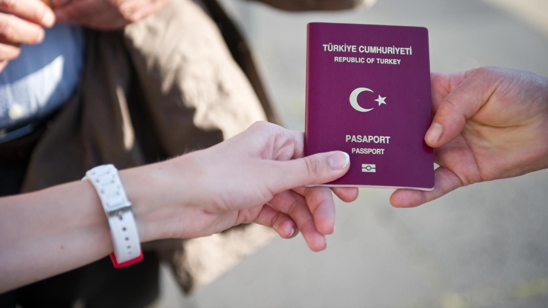 Eine türkische Wahlberechtigte zeigt am 03.08.2014 vor dem Olympiastadion in Berlin ihren türkischen Pass, um in das Wahlzentrum für die türkische Präsidentenwahl in Deutschland zu gelangen. Eine türkische Wahlberechtigte zeigt am 03.08.2014 vor dem Olympiastadion in Berlin ihren türkischen Pass, um in das Wahlzentrum für die türkische Präsidentenwahl in Deutschland zu gelangen.