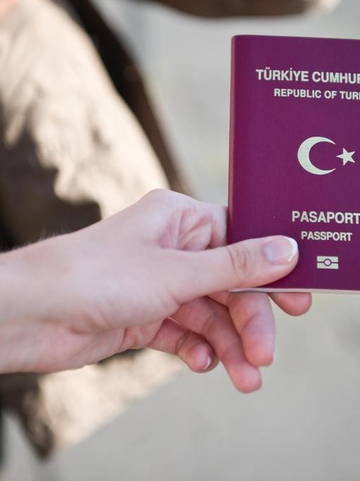 Eine türkische Wahlberechtigte zeigt am 03.08.2014 vor dem Olympiastadion in Berlin ihren türkischen Pass, um in das Wahlzentrum für die türkische Präsidentenwahl in Deutschland zu gelangen.