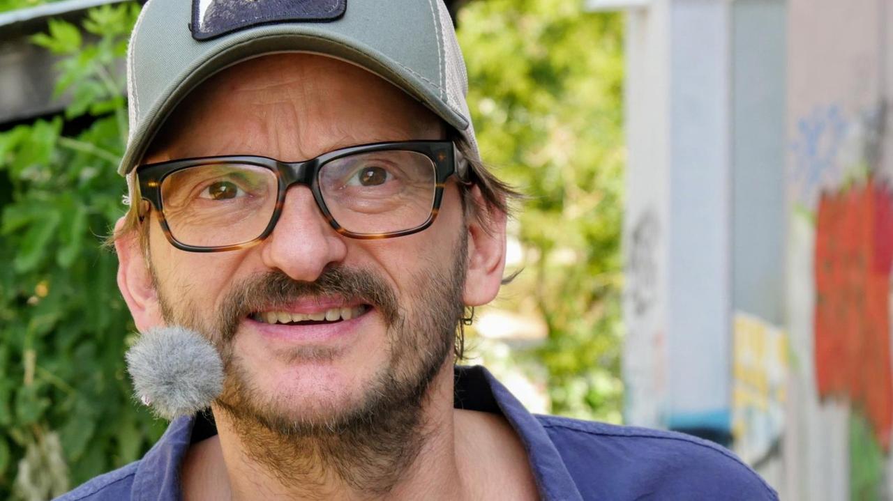 Der Schauspieler Milan Peschel schaut in die Kamera, er trägt eine Basecap, auf die ein Bär gedruckt ist. Der Schauspieler Milan Peschel schaut in die Kamera, er trägt eine Basecap, auf die ein Bär gedruckt ist.