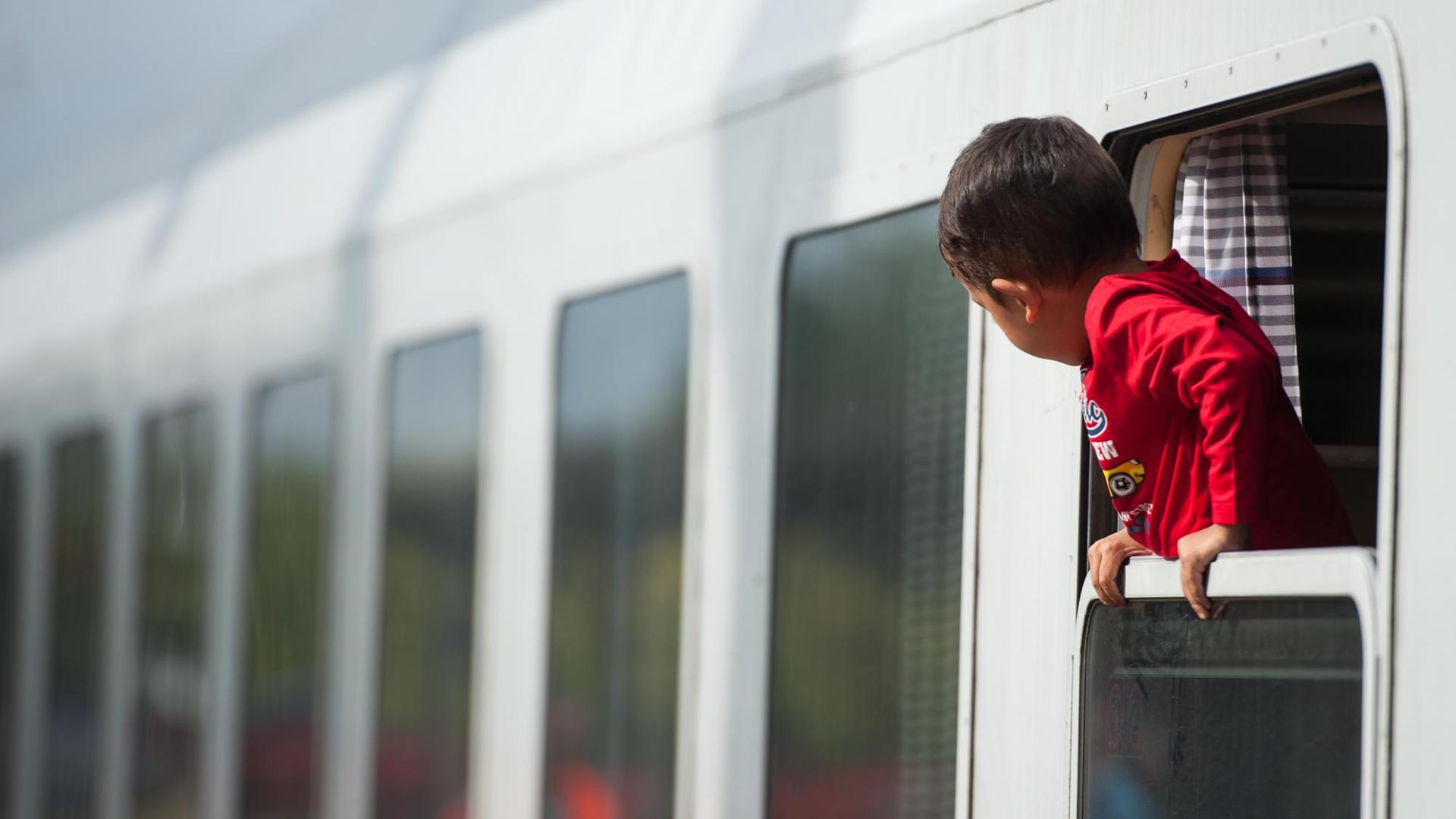 Ein Flüchtlingskind blickt am 13.09.2015 am Bahnhof von Uelzen (Niedersachsen) aus einem ankommenden Zug. Foto: Philipp Schulze/dpa | Ein Flüchtlingskind blickt am 13.09.2015 am Bahnhof von Uelzen (Niedersachsen) aus einem ankommenden Zug. Foto: Philipp Schulze/dpa |