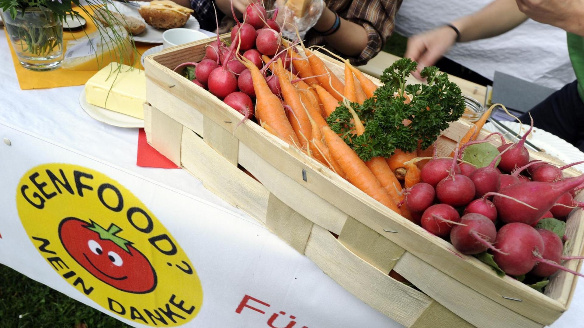Vor einem Plakat "Genfood? Nein Danke" wird genfreies Gemüse gezeigt. Vor einem Plakat "Genfood? Nein Danke" wird genfreies Gemüse gezeigt.