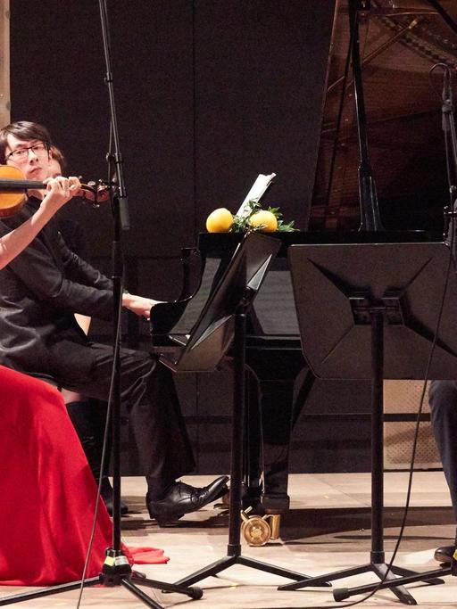 Die drei Musiker spielend in Aktion auf der Bühne