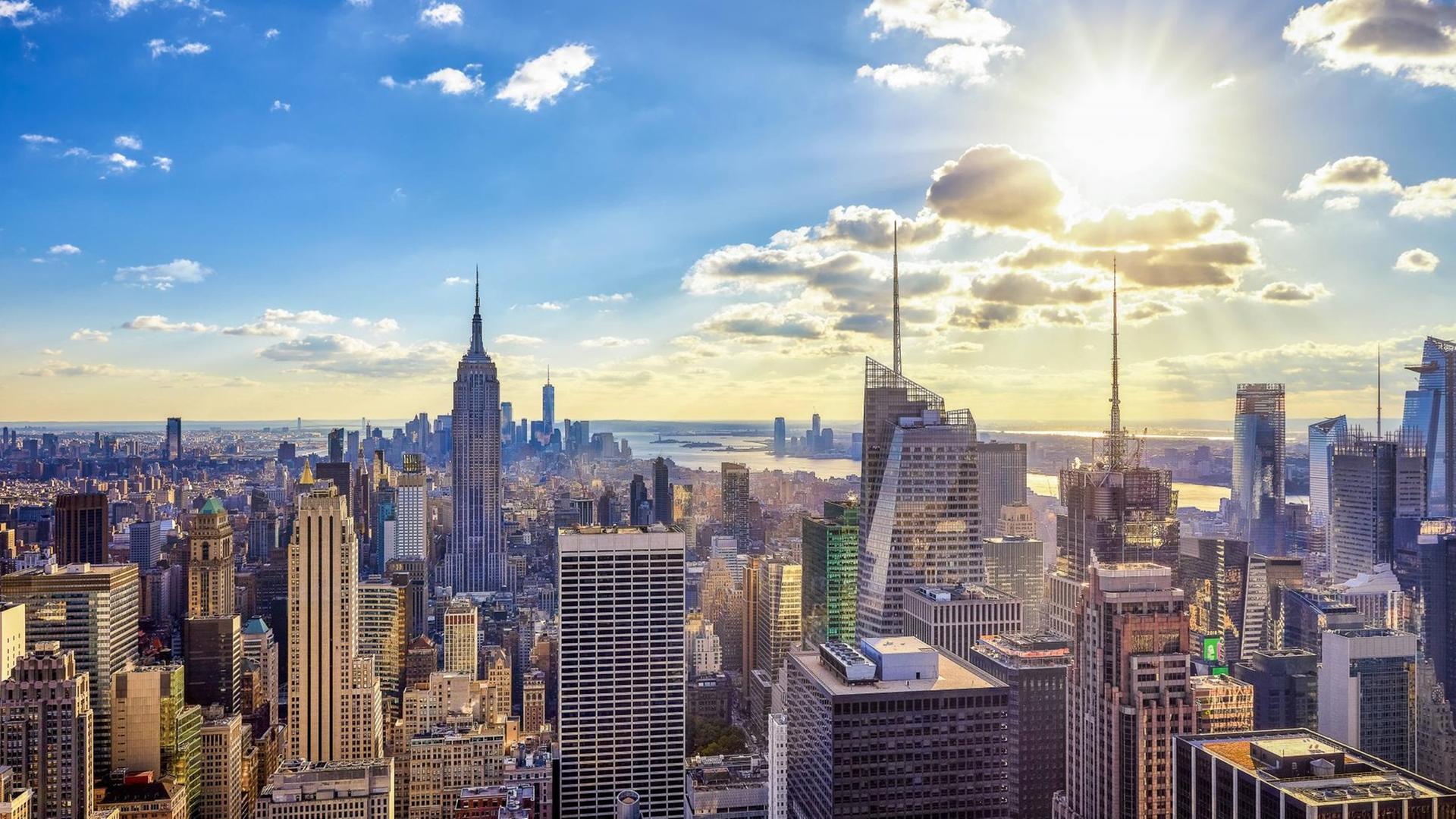 Gläsernen Hochhauskonstruktionen bilden die Skyline von New York und bilden eine Teil des Panoramas der Stadt im Gegenlicht der Sonne am Himmel.