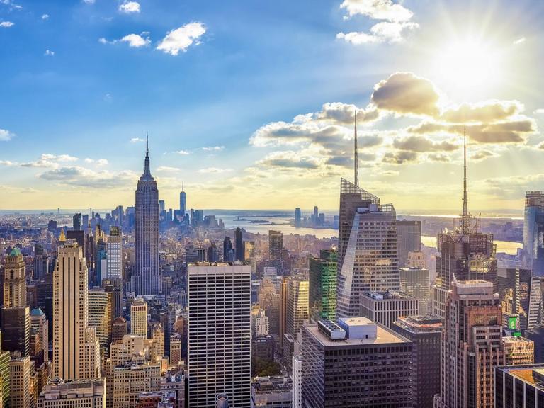 Gläsernen Hochhauskonstruktionen bilden die Skyline von New York und bilden eine Teil des Panoramas der Stadt im Gegenlicht der Sonne am Himmel.