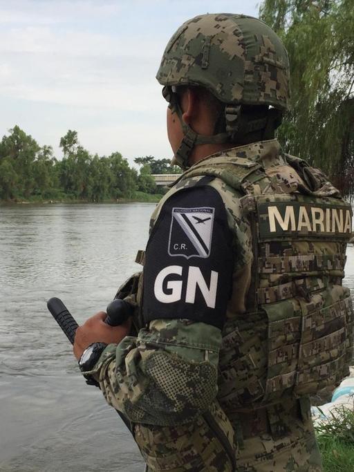 Bewaffnete Grenzpolizisten bewachen einen Fluss.