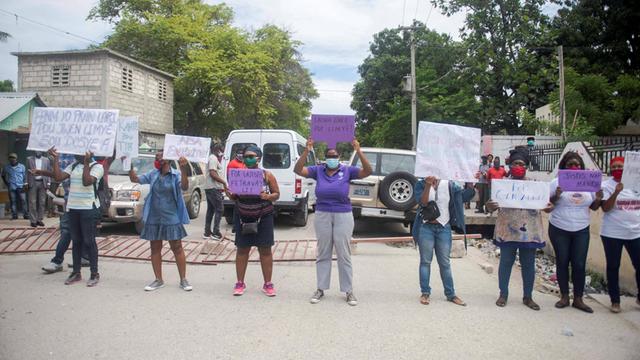 Frauen in Haiti demonstrieren mit Plakatenwährend der Anhörung des Präsidenten des haitianischen Fußballverbandes, Yves Jean Bart, für Frauenrechte.