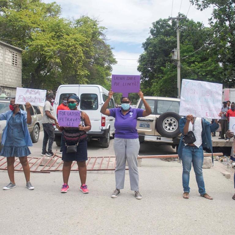 Frauen in Haiti demonstrieren mit Plakatenwährend der Anhörung des Präsidenten des haitianischen Fußballverbandes, Yves Jean Bart, für Frauenrechte.
