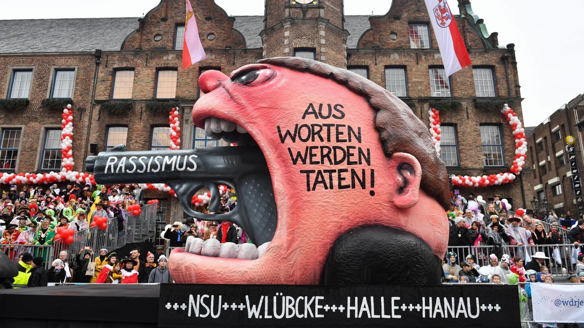 Ein Motivwagen des Rosenmontagzugs in Düsseldorf zeigt den Lauf einer Pistole, die aus einem Rachen ragt: "Rassismus - Aus Worten werden Taten!"
