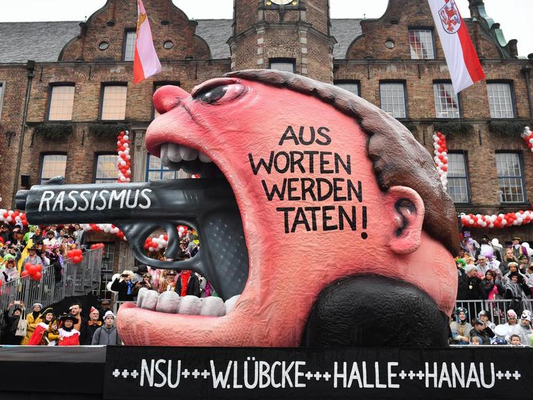 Ein Motivwagen des Rosenmontagzugs in Düsseldorf zeigt den Lauf einer Pistole, die aus einem Rachen ragt: "Rassismus - Aus Worten werden Taten!"