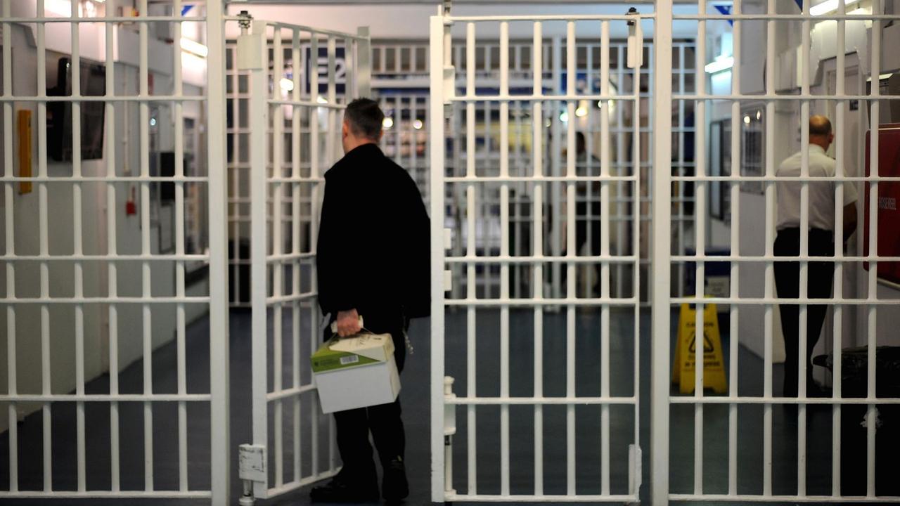 Mann mit Paket vor Gittertür in einem britischen Gefängnis