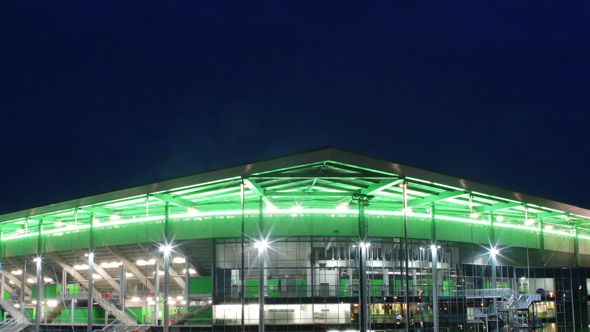 Die Teilansicht des Wolfsburger Stadions zeigt eine Ecke des mehrstöckigen Gebäudes, dessen überhängendes Dach grün angestrahlt ist. Die Teilansicht des Wolfsburger Stadions zeigt eine Ecke des mehrstöckigen Gebäudes, dessen überhängendes Dach grün angestrahlt ist.