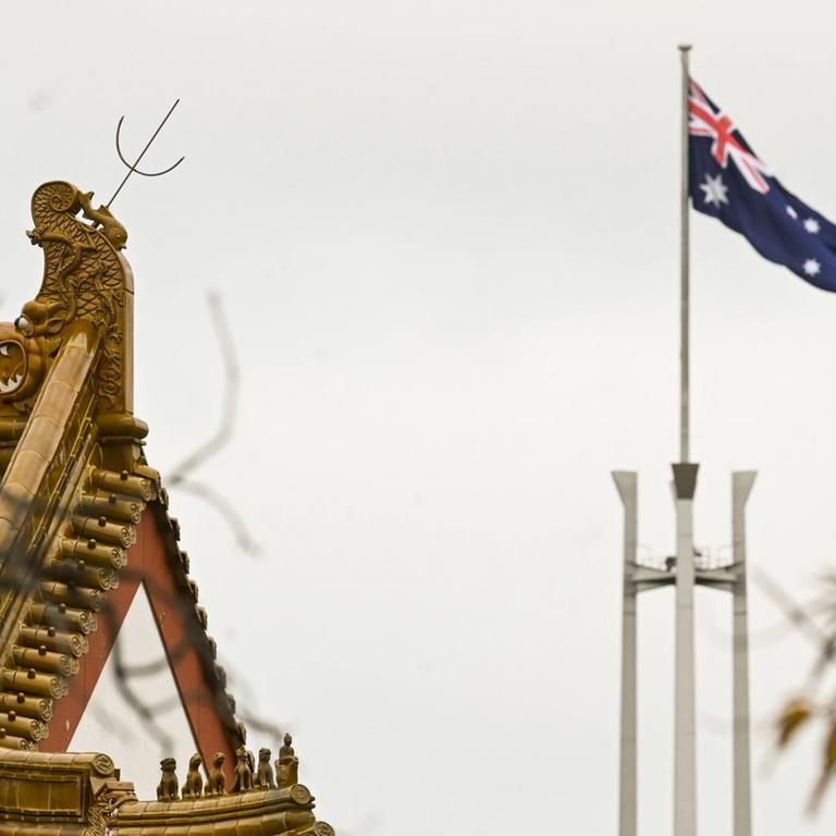 Flagge des australischen Parlament hinter dem Dachstuhl der chinesischen Botschaft in Canbera