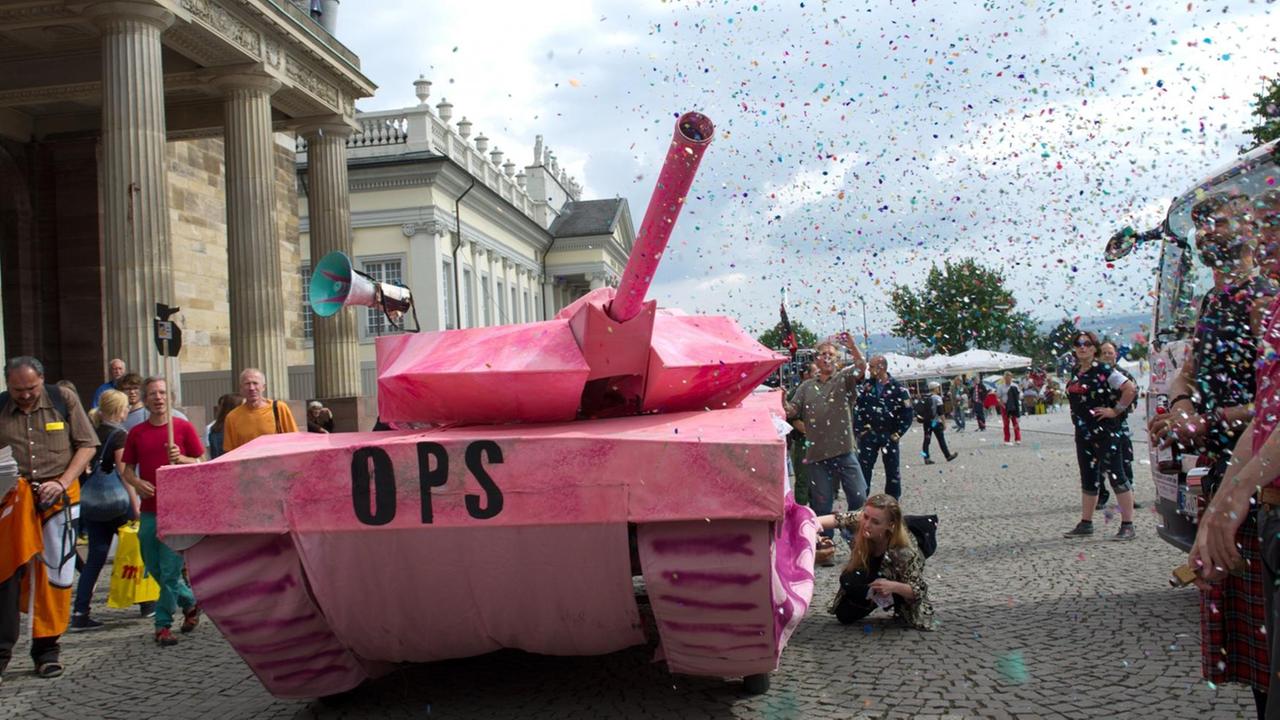 Ein rosaroter Panzer-Nachbau verschießt am Freitag (31.08.2012) auf dem Kasseler Friedrichsplatz Konfetti mit Pressluft. Rund 350 Menschen haben gegen deutsche Waffenexporte demonstriert. Nach Angaben der Polizei zogen sie friedlich von der Innenstadt zum Werk des Rüstungsunternehmens Krauss-Maffei Wegmann. Aufgerufen zu der Kundgebung hatte ein Bündnis mehrerer Friedensinitiativen, Studentengruppen und Parteien.
