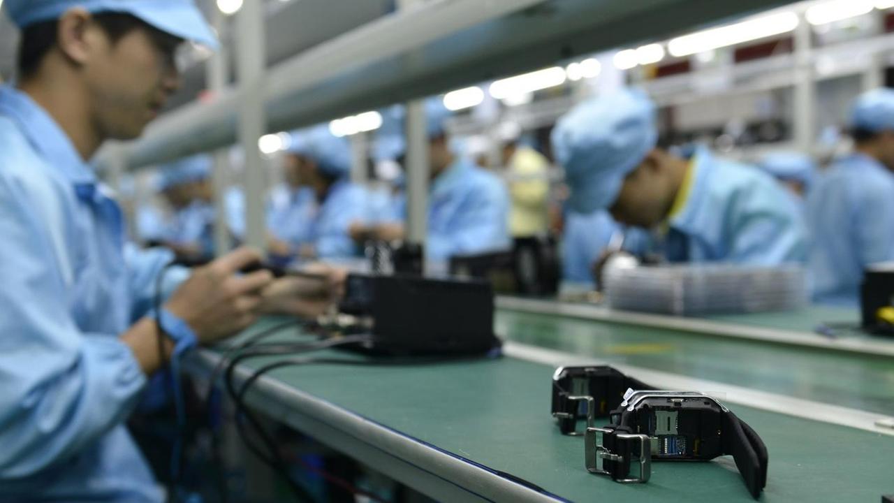 Chinesische Arbeiter bauen eine Smart-Watch zusammen. Chinesische Arbeiter bauen eine Smart-Watch zusammen.