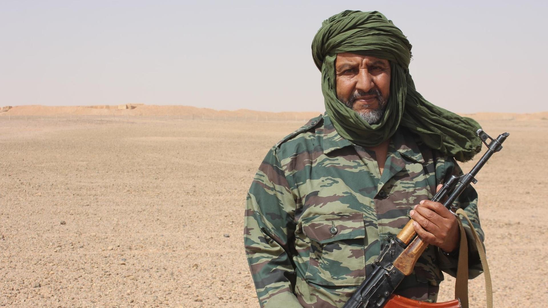 Soldat mit Gewehr in der Wüste Soldat mit Gewehr in der Wüste
