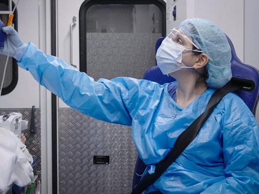 Eine Frau in Schutzmaske und Schutzkleidung im Krankenwagen