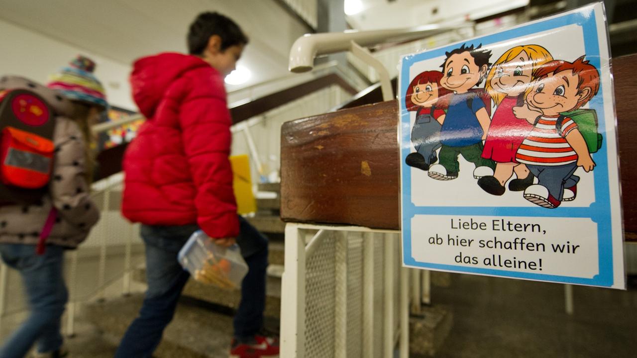 An einer Grundschule in Stuttgart laufen Schüler an einem Schild vorbei, das überfürsorgliche Eltern ermahnt, ihre Kinder alleine weitergehen zu lassen. An einer Grundschule in Stuttgart laufen Schüler an einem Schild vorbei, das überfürsorgliche Eltern ermahnt, ihre Kinder alleine weitergehen zu lassen.