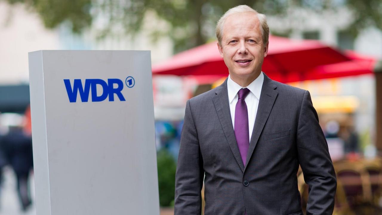 Buhrow steht in der Kölner Innenstadt neben einer grauen Säule mit dem WDR-Schriftzug. Buhrow steht in der Kölner Innenstadt neben einer grauen Säule mit dem WDR-Schriftzug.
