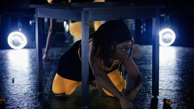 DieSchauspielerin Armelle Charlie Ntodouah Etongo aus Martin Ambaras Inszenierung "Swatche Baartman: Une histoire. Une vie" versteckt sich unter einem Tisch.