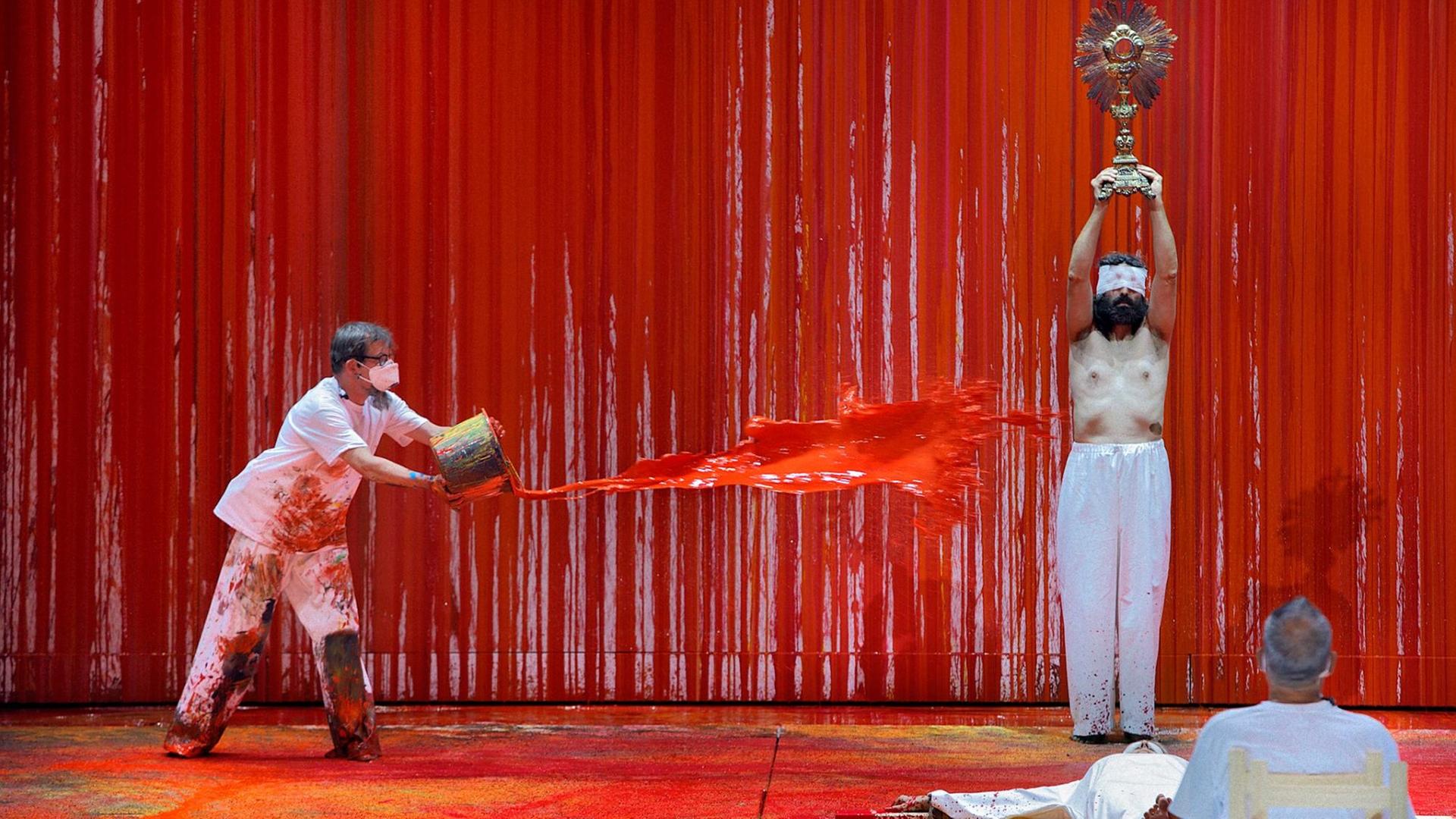Ein Malassistent (l) des österreichischen Aktionskünstlers Hermann Nitsch schüttet während der Fotoprobe zur Richard Wagners "Walküre" rote Farbe auf einen Statisten der Festspiele. Das Bühnenbild wurde in diesem Jahr von "Blutkünstler" Hermann Nitsch gestaltet. Die Wagner-Oper feierte am 29.07.2021 Premiere bei den Bayreuther Festspielen 2021. Ein Malassistent (l) des österreichischen Aktionskünstlers Hermann Nitsch schüttet während der Fotoprobe zur Richard Wagners "Walküre" rote Farbe auf einen Statisten der Festspiele. Das Bühnenbild wurde in diesem Jahr von "Blutkünstler" Hermann Nitsch gestaltet. Die Wagner-Oper feierte am 29.07.2021 Premiere bei den Bayreuther Festspielen 2021.