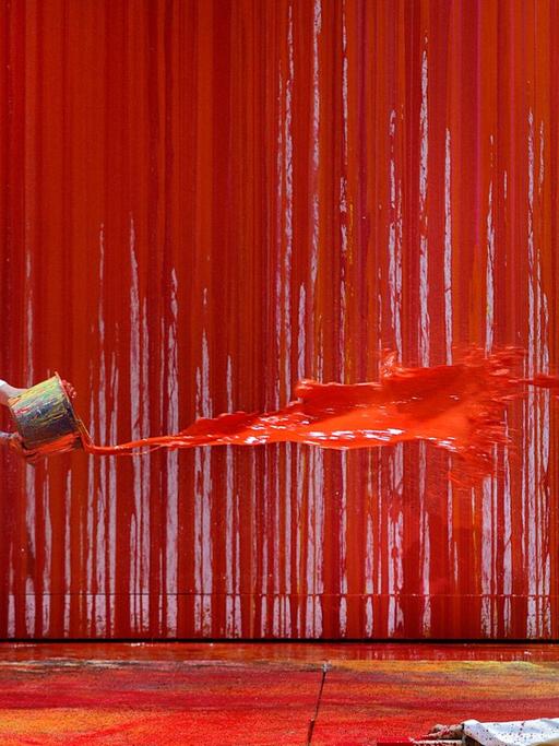 Ein Malassistent (l) des österreichischen Aktionskünstlers Hermann Nitsch schüttet während der Fotoprobe zur Richard Wagners "Walküre" rote Farbe auf einen Statisten der Festspiele. Das Bühnenbild wurde in diesem Jahr von "Blutkünstler" Hermann Nitsch gestaltet. Die Wagner-Oper feierte am 29.07.2021 Premiere bei den Bayreuther Festspielen 2021.