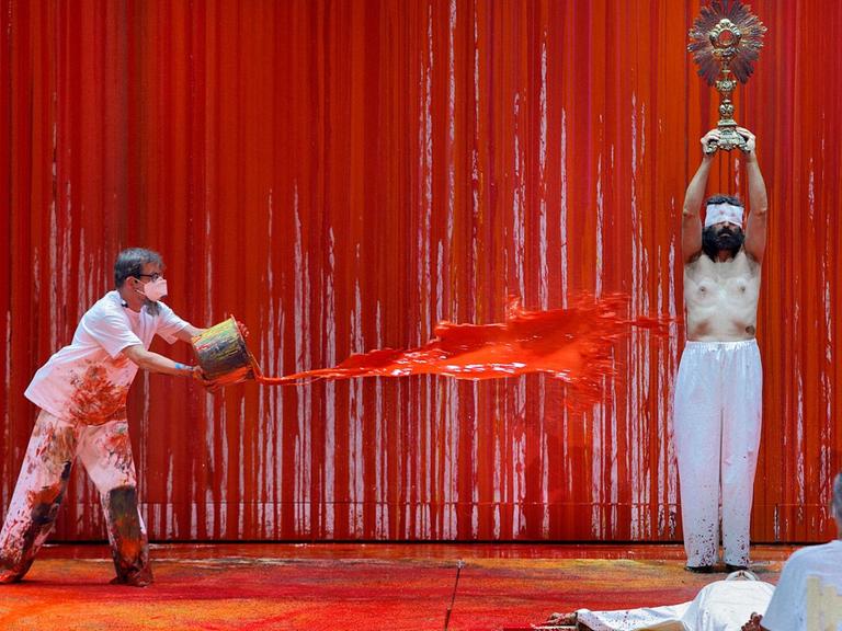 Ein Malassistent (l) des österreichischen Aktionskünstlers Hermann Nitsch schüttet während der Fotoprobe zur Richard Wagners "Walküre" rote Farbe auf einen Statisten der Festspiele. Das Bühnenbild wurde in diesem Jahr von "Blutkünstler" Hermann Nitsch gestaltet. Die Wagner-Oper feierte am 29.07.2021 Premiere bei den Bayreuther Festspielen 2021.