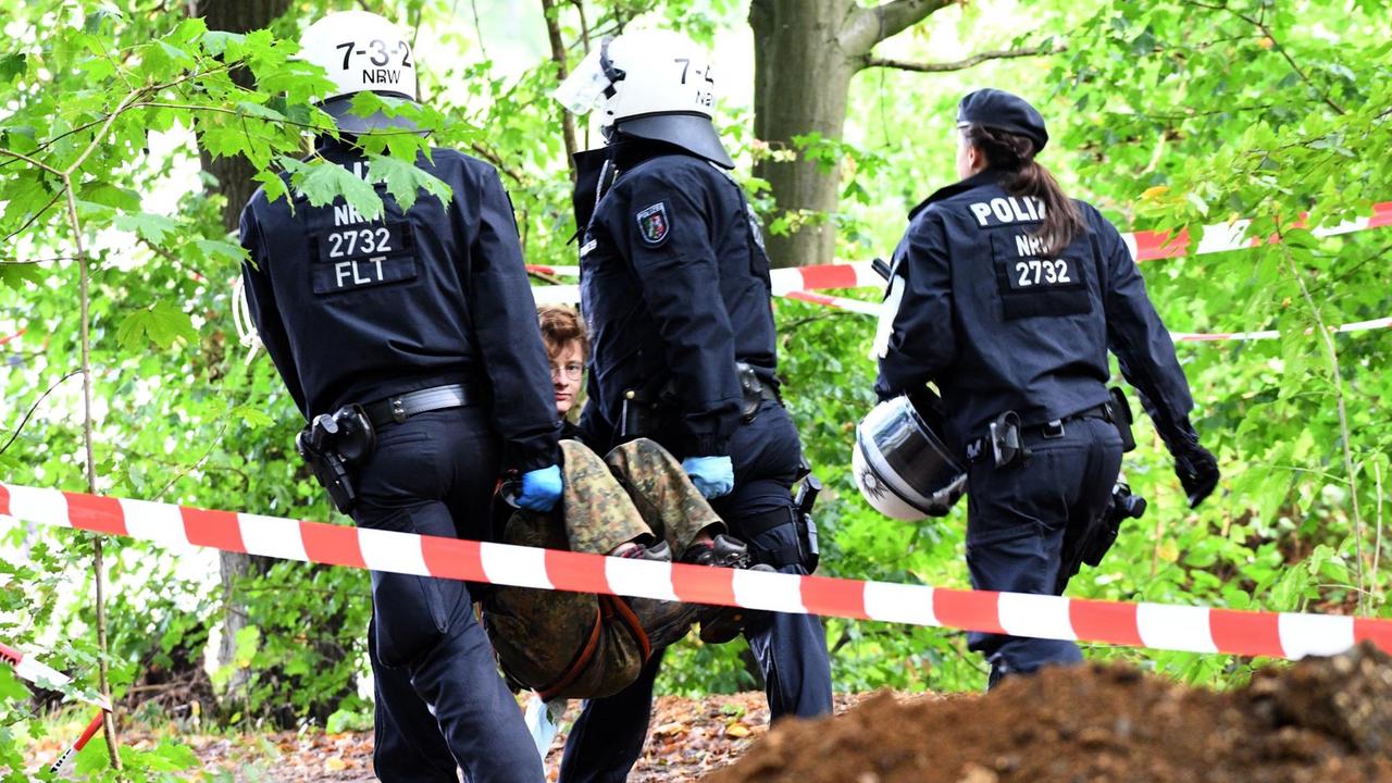 Polizisten tragen im Hambacher Forst eine Aktivistin aus dem Wald.