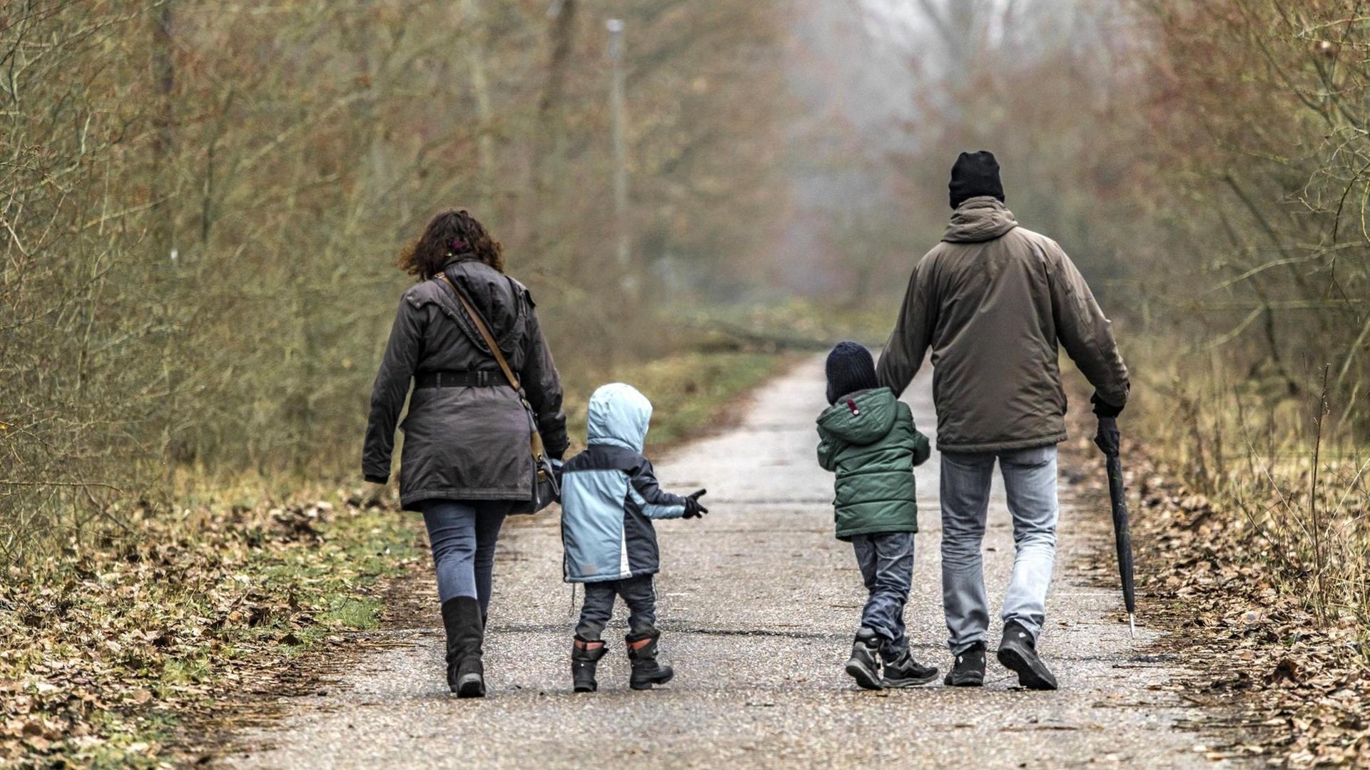Eine Familie beim Spaziergang. Mutter und Vater laufen außen und die Kinder in der Mitte aber weit voneinander entfernt. Eine Familie beim Spaziergang. Mutter und Vater laufen außen und die Kinder in der Mitte aber weit voneinander entfernt.