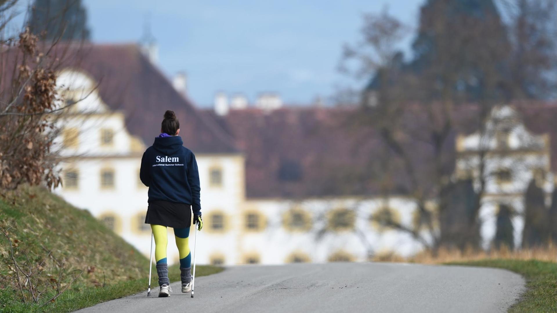 Eine Internatsschülerin läuft vor dem Schloss Salem (Baden-Württemberg) mit Walking-Stöcken einen Weg entlang. Eine Internatsschülerin läuft vor dem Schloss Salem (Baden-Württemberg) mit Walking-Stöcken einen Weg entlang.