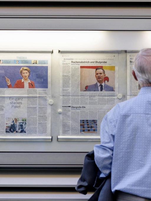 Ein Mann steht vor einer Zeitung in einem Schaukasten
