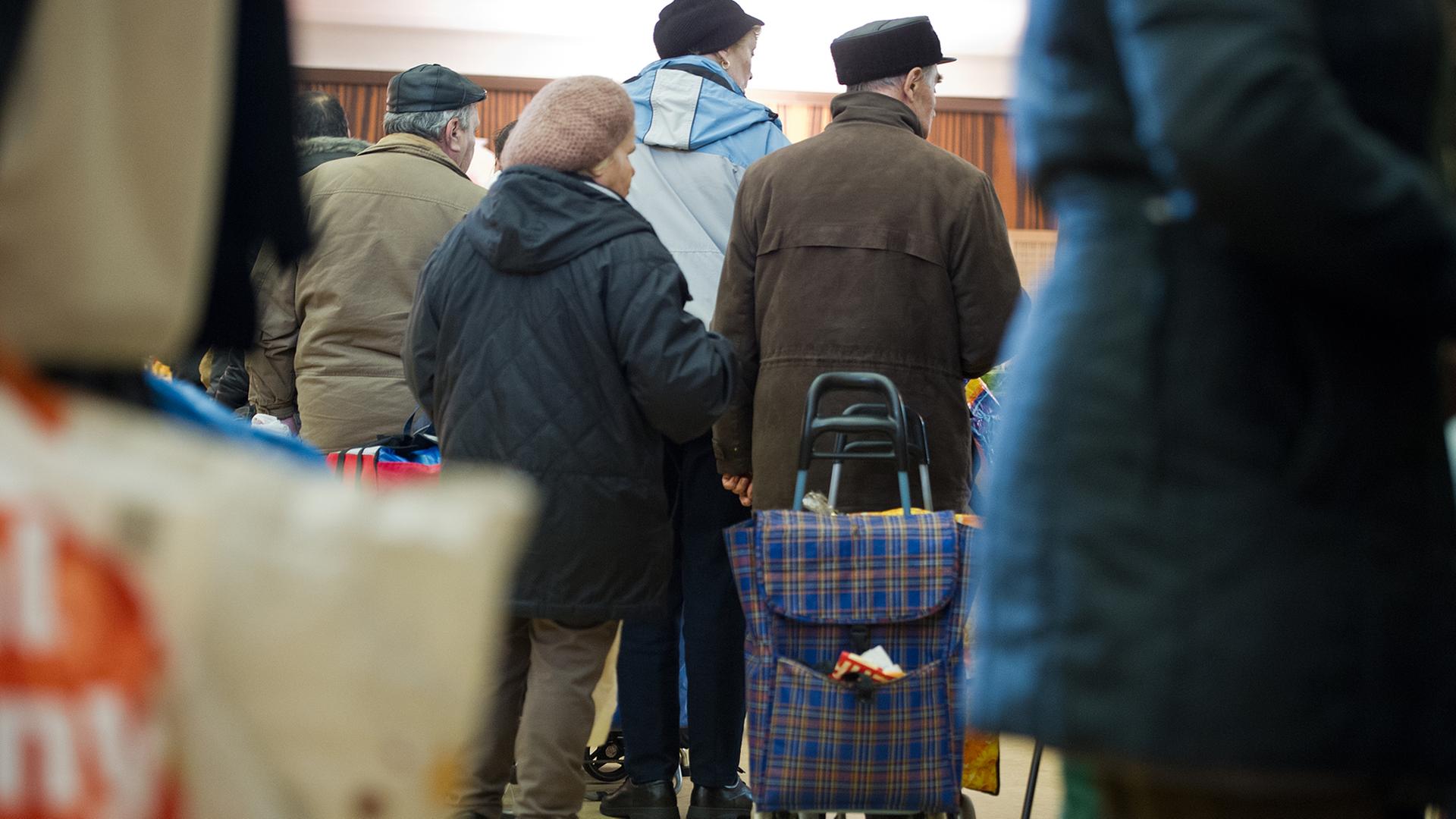 In einer langen Schlange warten Bedürftige in der Tafel der Stephanusgemeinde in Wiesbaden (Hessen) am 13.12.2012 auf die Ausgabe von Lebensmitteln.