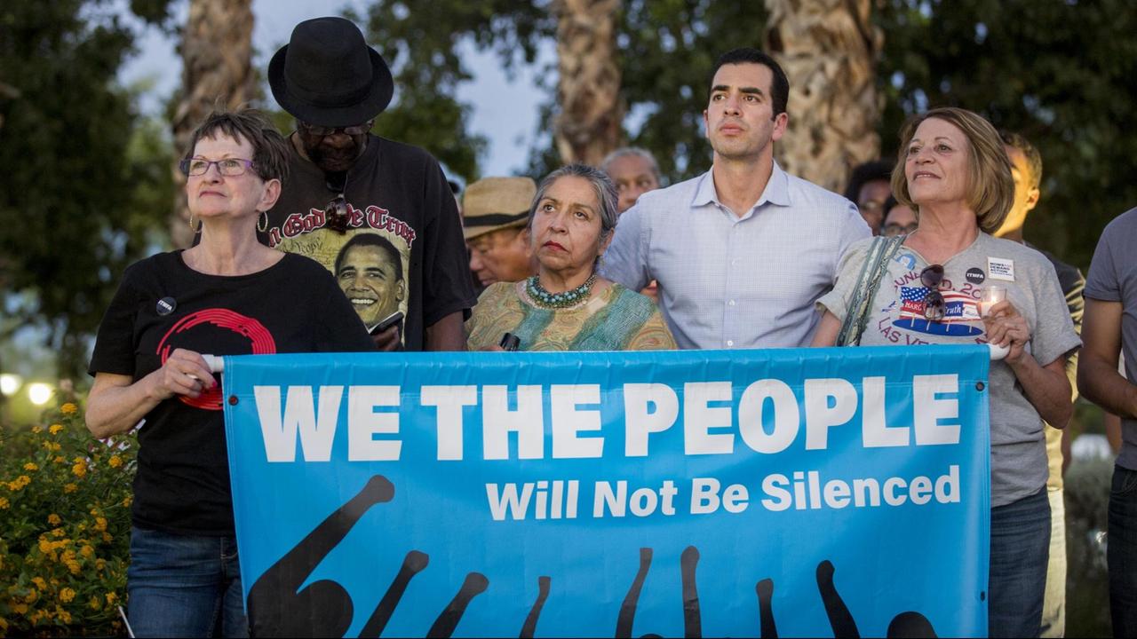 Mehrere Menschen demonstrieren in Las Vegas gegen rechte Gewalt in den USA. Auf ihrem Plakat steht übersetzt: Wir, das Volk, werden nicht zum Schweigen gebracht werden. Mehrere Menschen demonstrieren in Las Vegas gegen rechte Gewalt in den USA. Auf ihrem Plakat steht übersetzt: Wir, das Volk, werden nicht zum Schweigen gebracht werden.