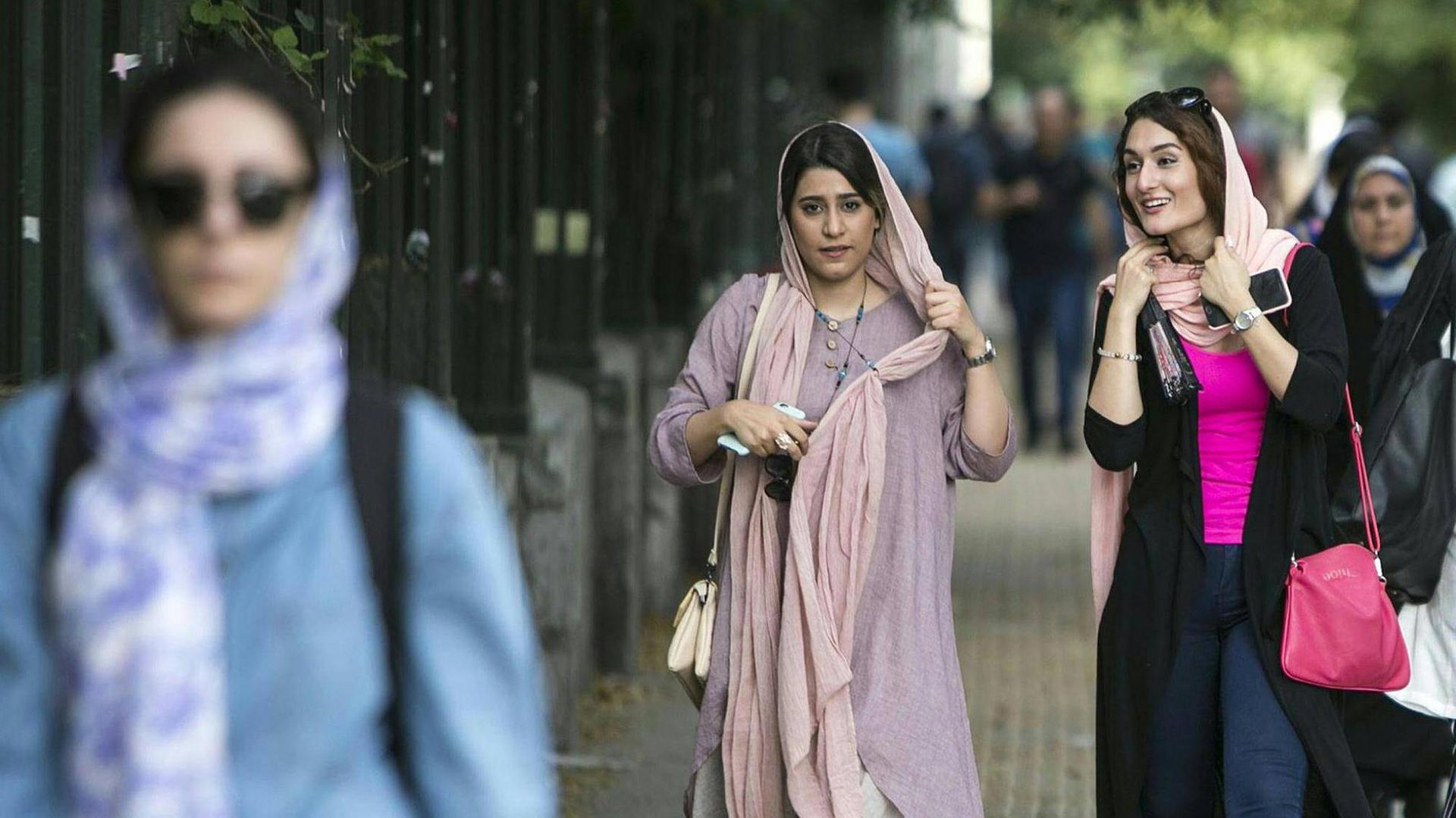 Iranische Frauen laufen eine Straße in der Teheraner Innenstadt entlang.