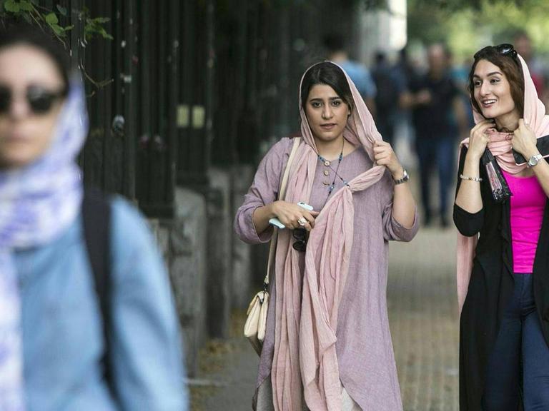 Iranische Frauen laufen eine Straße in der Teheraner Innenstadt entlang.