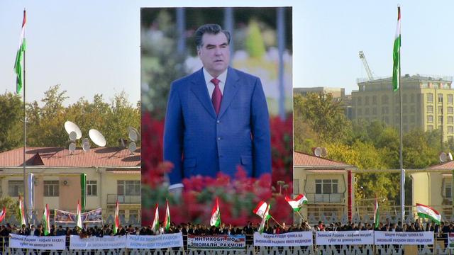 Anhänger von Präsident Emomalii Rahmon schwenken Fahnen vor einem riesigen Plakat des autoritären Präsidenten