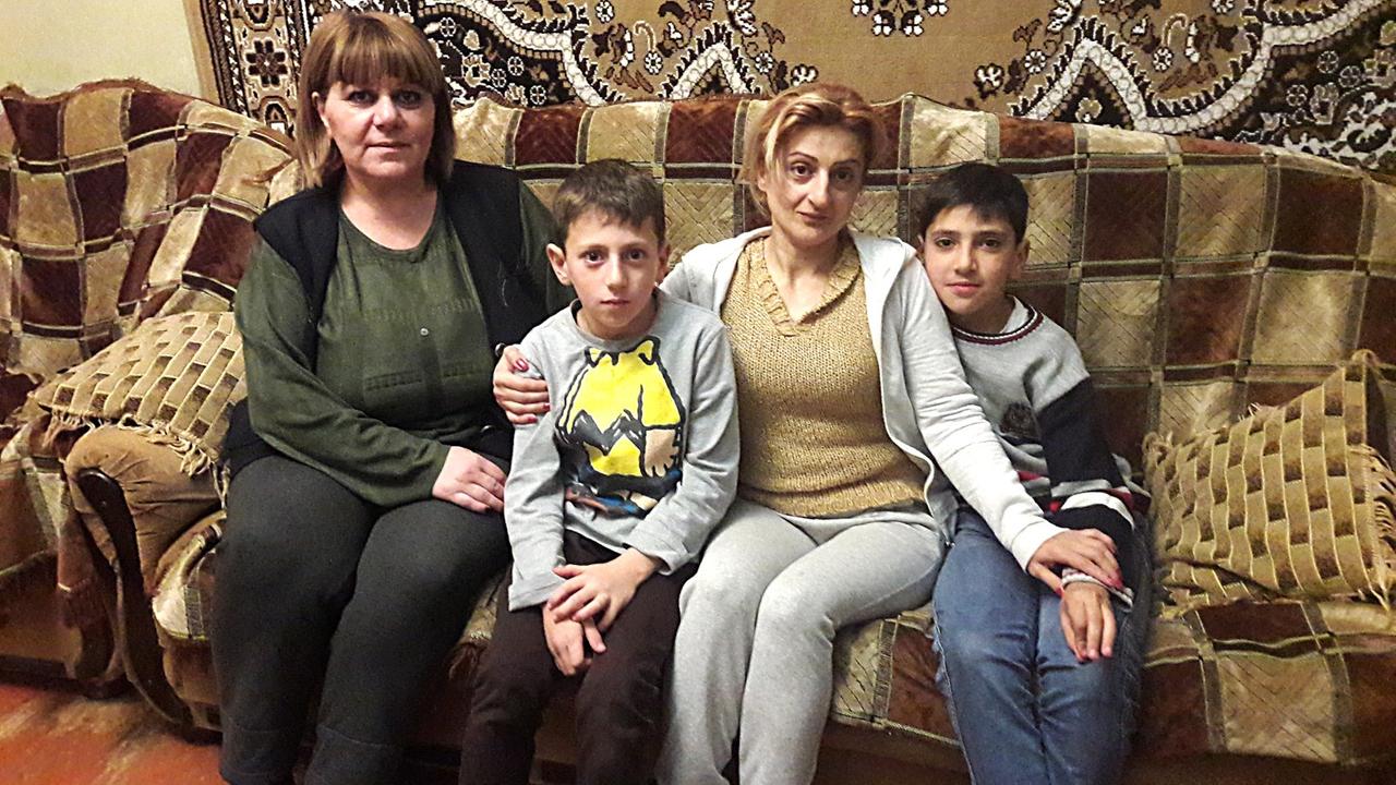 Zwei Frauen sitzen mit zwei Jungen auf dem Sofa Zwei Frauen sitzen mit zwei Jungen auf dem Sofa