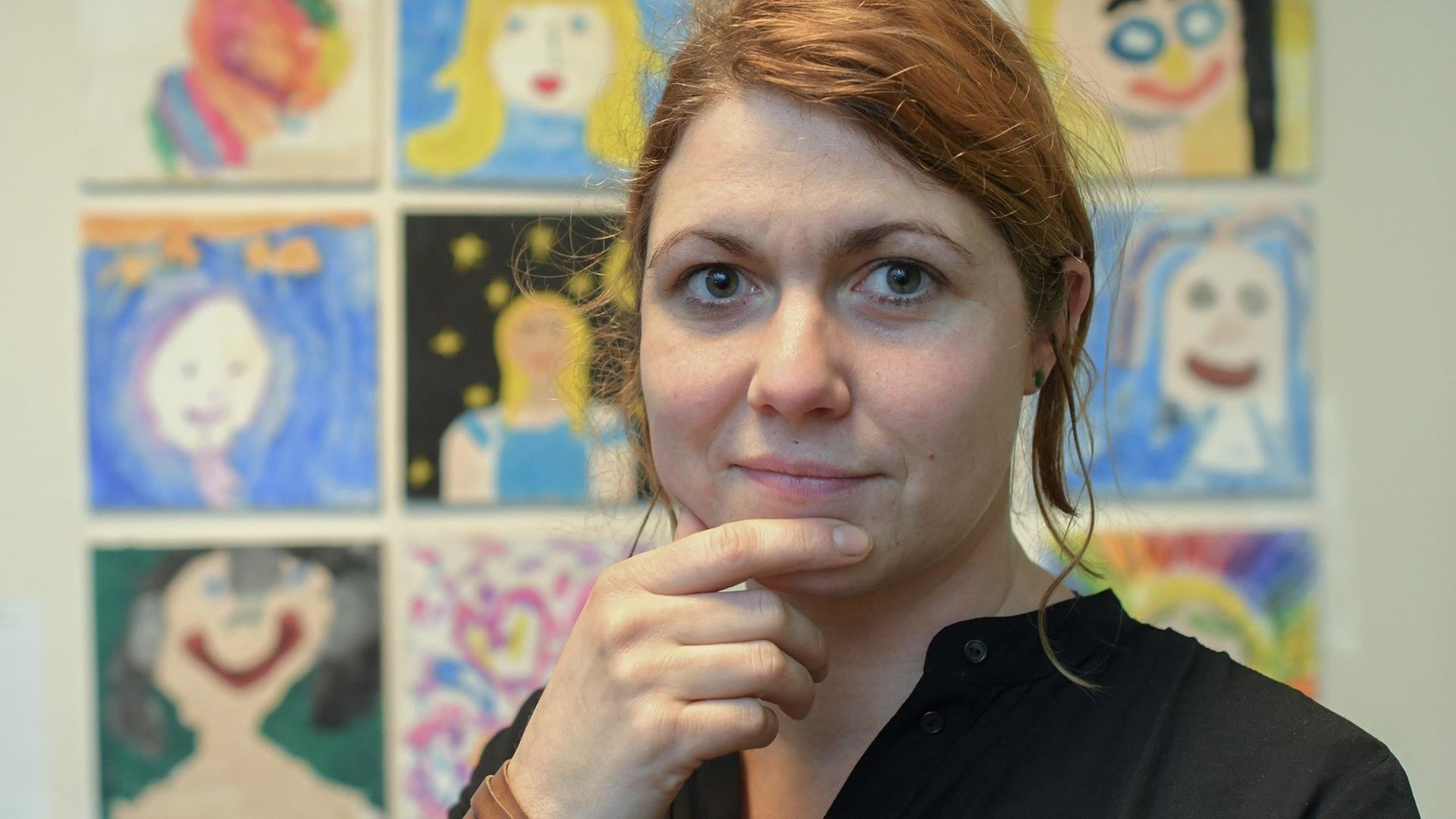 Carolin Schönwald steht im Kinder-Kunst-Zentrum vor Zeichnungen von Schülern.