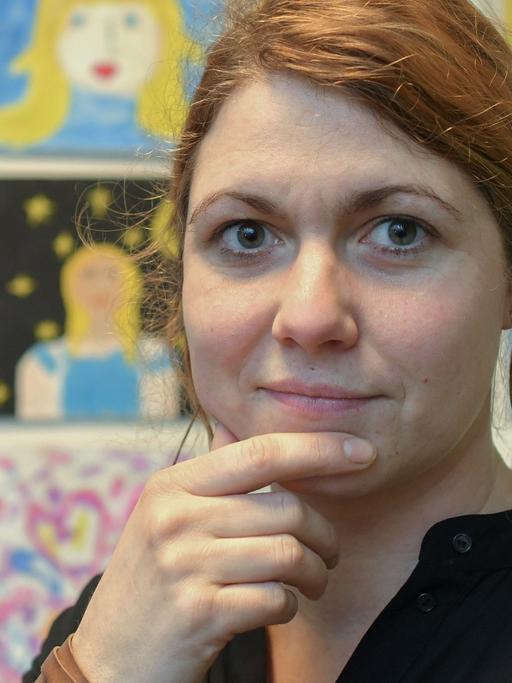 Carolin Schönwald steht im Kinder-Kunst-Zentrum vor Zeichnungen von Schülern.