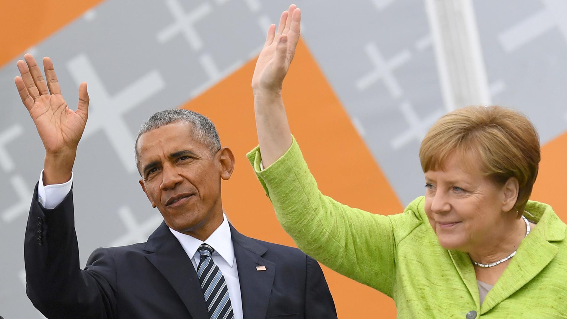Bundeskanzlerin Angela Merkel und Ex-US-Präsident Barack Obama winken am 25. Mai 2017 in Berlin vor dem Brandenburger Tor beim Deutschem Evangelischem Kirchentag Besuchern zu.