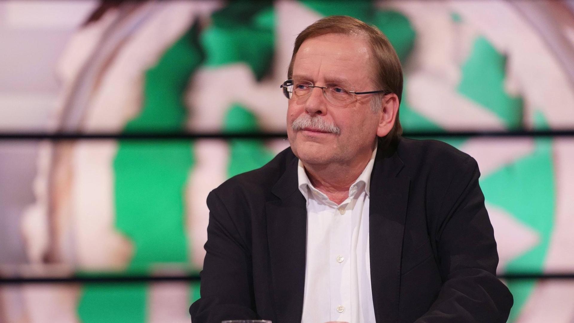 Rainer Koch sitzt vor einer Grafik eines verschwommenen DFB-Wappens. Rainer Koch sitzt vor einer Grafik eines verschwommenen DFB-Wappens.