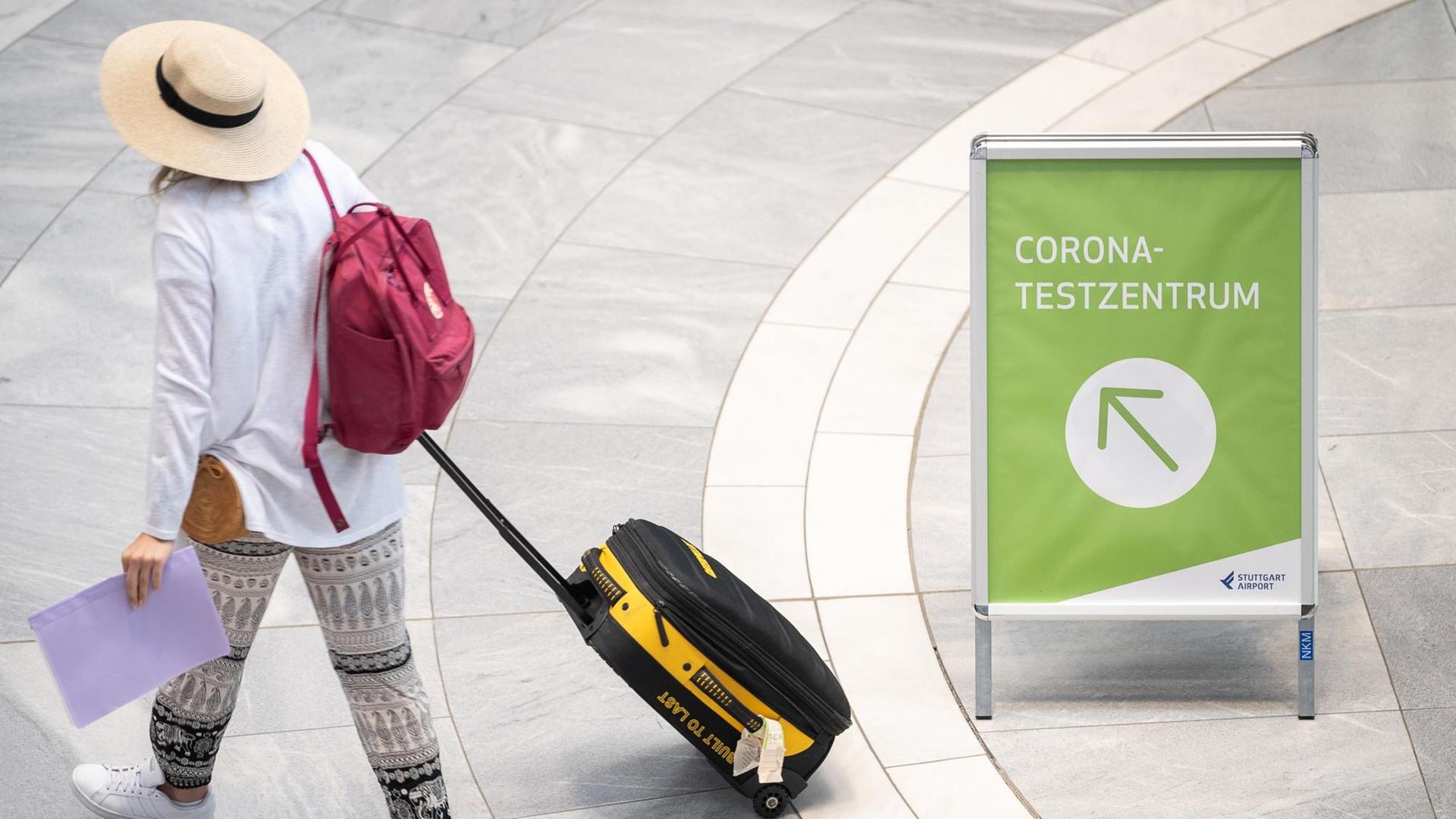 03.08.2020 - Reisende mit Rollkoffer und Sonnenhut, daneben ein Wegweiser zum "Corona-Testzentrum" am Stuttgarter Flughafen 03.08.2020 - Reisende mit Rollkoffer und Sonnenhut, daneben ein Wegweiser zum "Corona-Testzentrum" am Stuttgarter Flughafen