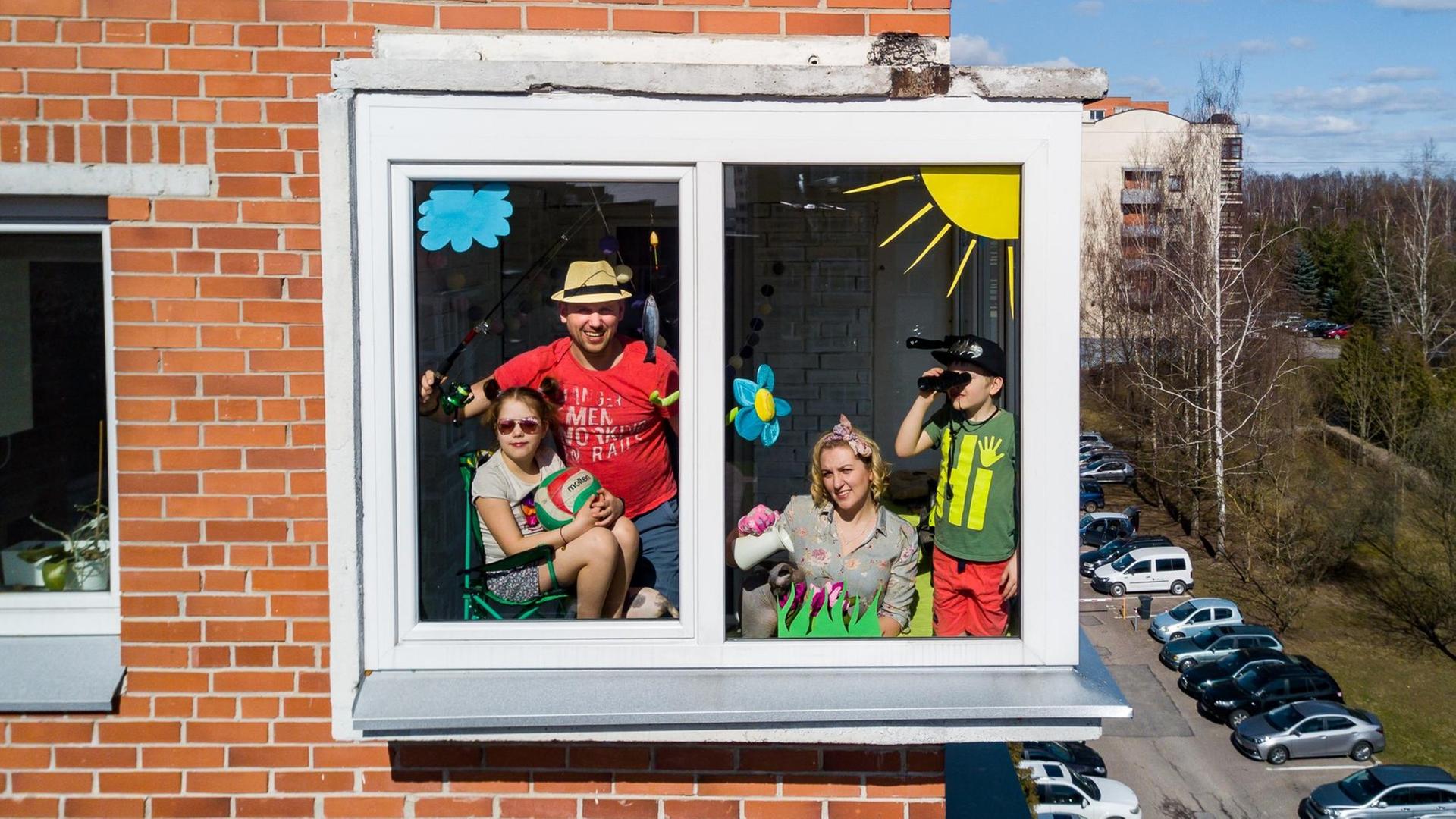 Das Foto zeigt eine Familie, die sich hinter einem Fenster ihrer Wohnung versammelt hat und sich offenbar von der Coronapandemie nicht unterkriegen lässt. Das Foto zeigt eine Familie, die sich hinter einem Fenster ihrer Wohnung versammelt hat und sich offenbar von der Coronapandemie nicht unterkriegen lässt.