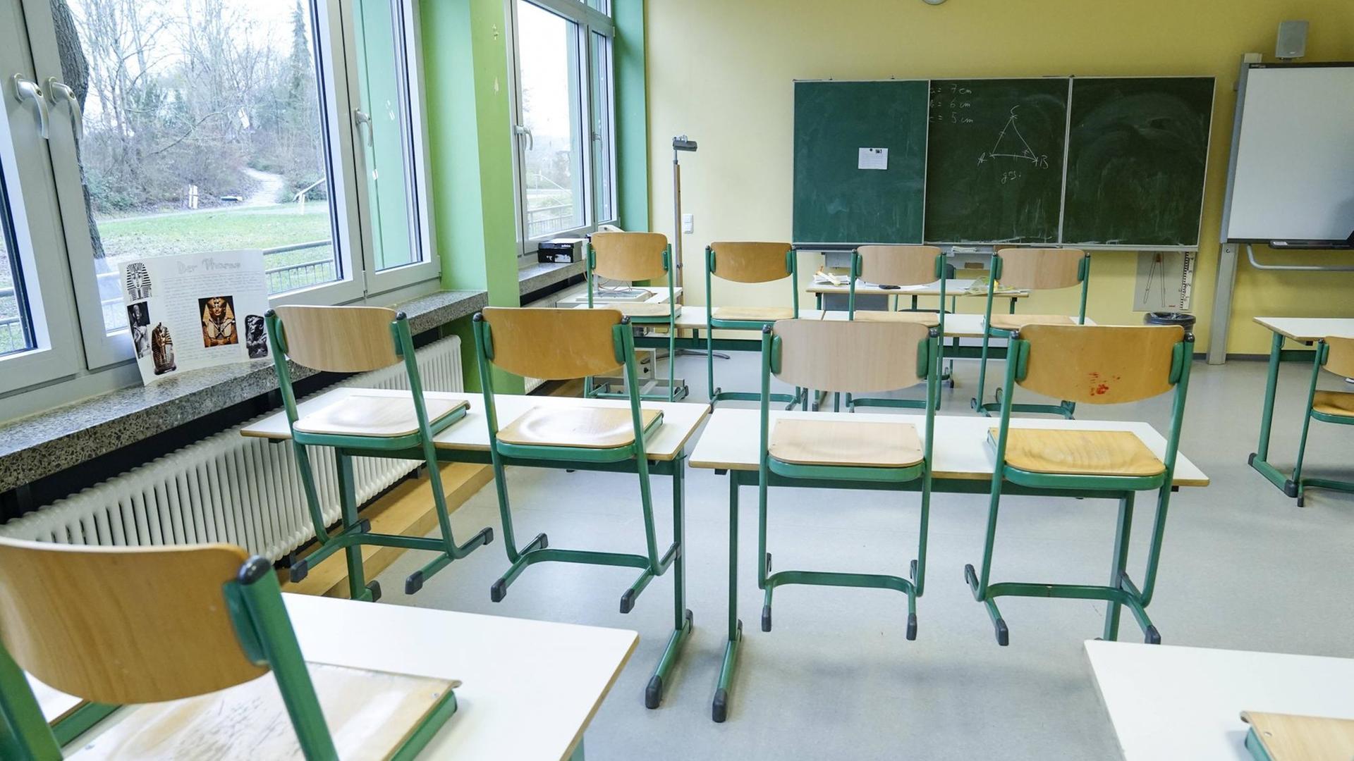 Klassenzimmer einer Schule mit einer Tafel und hochgestellten Stühlen Klassenzimmer einer Schule mit einer Tafel und hochgestellten Stühlen