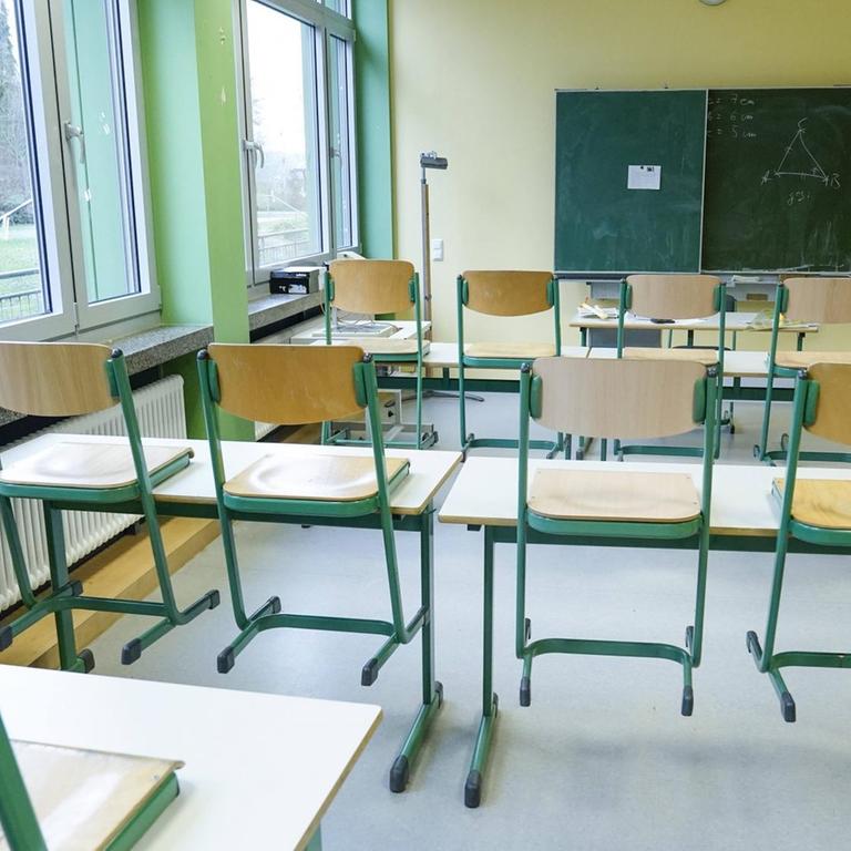 Klassenzimmer einer Schule mit einer Tafel und hochgestellten Stühlen 