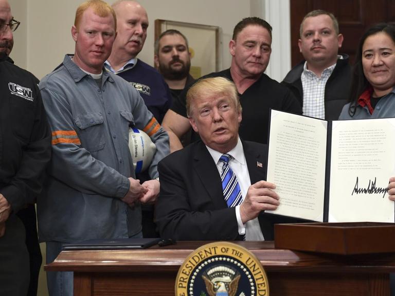 Das Bild zeigt US-Präsident Trump nach der Unterzeichnung seiner Verordnung über Schutzzölle. Er ist umringt von amerikanischen Stahlarbeitern.